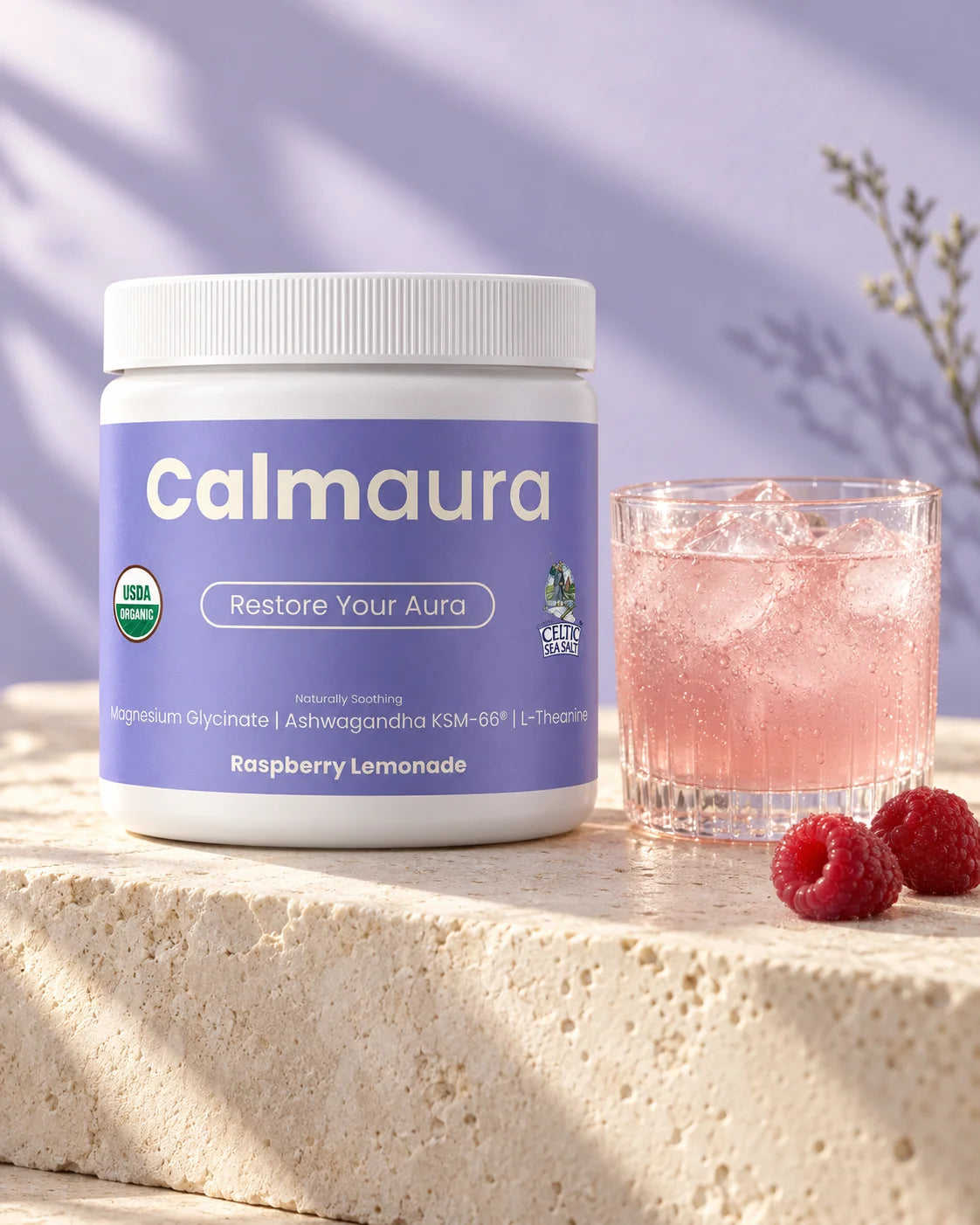 Calmaura Raspberry Lemonade beside a glass on a sunlit stone counter